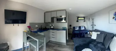 a living room with a blue couch and a table at Little bay cabin in Oban