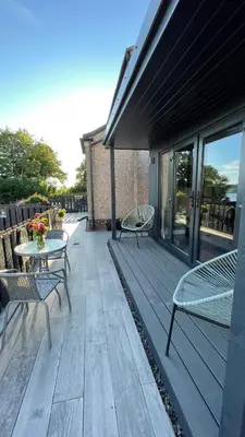 a wooden deck with two chairs and a table at Little bay cabin in Oban