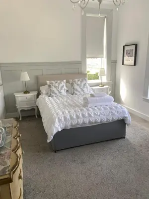 a bedroom with a bed and two tables and a window at Giffnock Rooms in Giffnock
