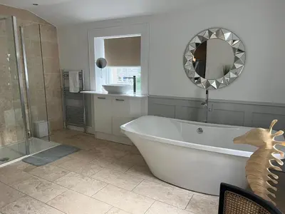 a bathroom with a tub and a shower and a mirror at Giffnock Rooms in Giffnock