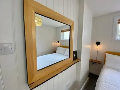 a mirror on a wall with a bed in a room at Westbay Seafront Apartment in Oban