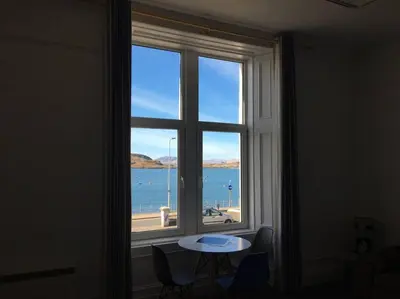 a window with a table and a view of the ocean at Westbay Seafront Apartment in Oban