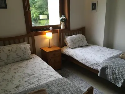two beds in a room with a lamp and a window at Heron’s View in Arrochar