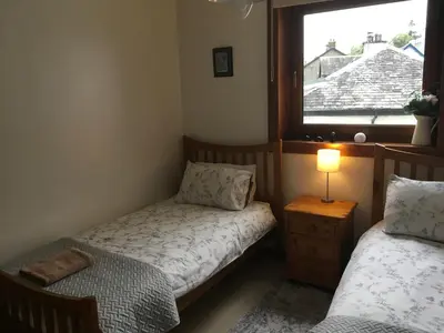 a small bedroom with two beds and a window at Heron’s View in Arrochar