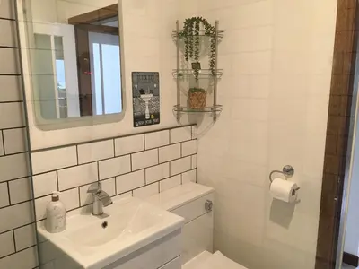 a white bathroom with a sink and a mirror at Heron’s View in Arrochar