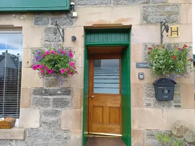 a building with a wooden door and flowers on it at Craiglea Thistle in Killin