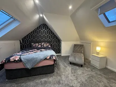 a attic bedroom with a bed and a chair at Captivating 3 bedroom home with conservatory in Hamilton