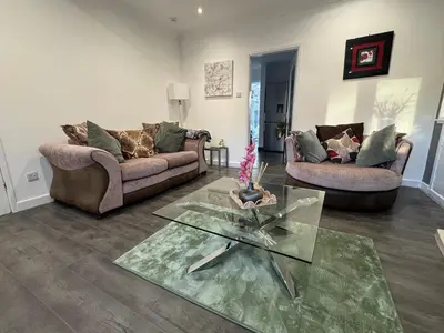 a living room with two couches and a glass table at Captivating 3 bedroom home with conservatory in Hamilton