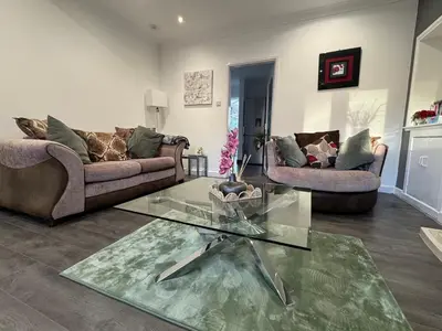 a living room with two couches and a glass table at Captivating 3 bedroom home with conservatory in Hamilton