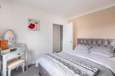 a bedroom with a bed and a desk with a mirror at Captivating 3 bedroom home with conservatory in Hamilton