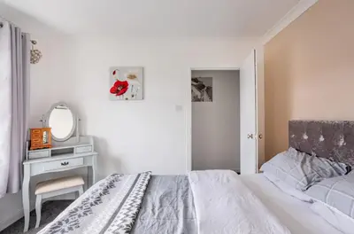 a white bedroom with a bed and a mirror at Captivating 3 bedroom home with conservatory in Hamilton