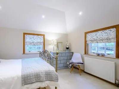 a bedroom with a bed and a desk and two windows at The Bield in Aberfoyle