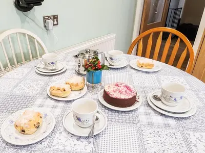 a table with plates of food and cups and a cake at Seven Seasons in Caldercruix