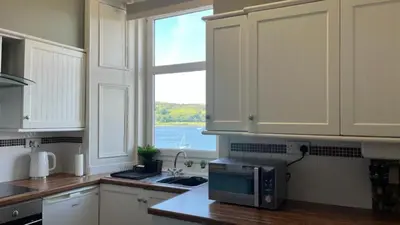a kitchen with a microwave on a counter with a window at Beautiful Upper Apartment/Stunning Sea Views, Isle of Bute in Port Bannatyne