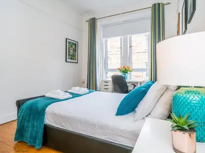 a bedroom with a large bed with blue pillows at Superb 1 Bed Flat in Traditional Victorian Building - Pass the Keys in Edinburgh
