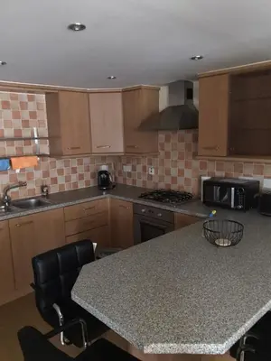 a kitchen with wooden cabinets and a table with a microwave at Beautiful 3-Bed Apartment in Gourock in Gourock