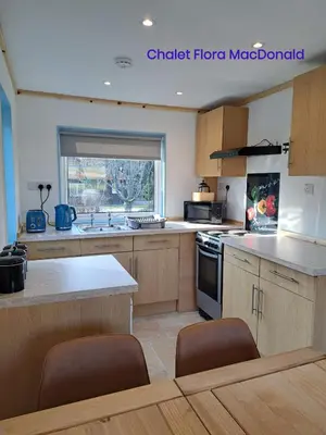 a kitchen with wooden cabinets and a stove top oven at Airdeny Chalets in Taynuilt