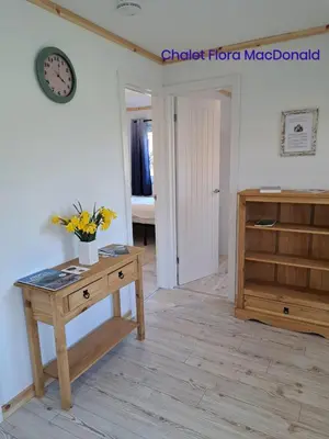 a room with a table and a clock on the wall at Airdeny Chalets in Taynuilt