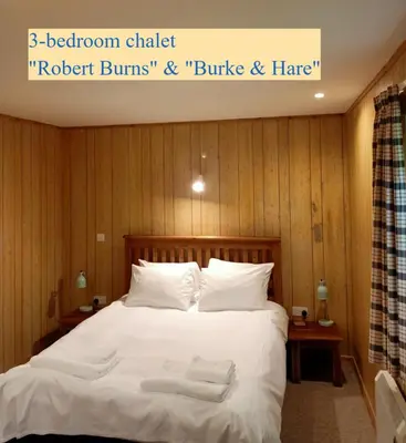 a bedroom with a bed with white sheets and pillows at Airdeny Chalets in Taynuilt