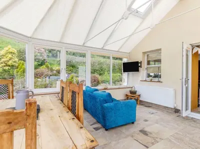 a living room with a blue couch and a tv at 3 Bedroom luxury home, hot tub, stunning views of Killin, sitting on the River Dochart in Killin