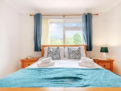a bedroom with a large bed with a blue blanket at 3 Bedroom luxury home, hot tub, stunning views of Killin, sitting on the River Dochart in Killin
