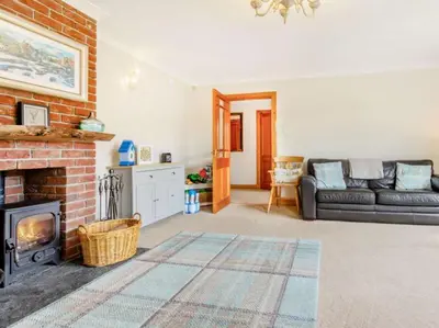 a living room with a couch and a fireplace at 3 Bedroom luxury home, hot tub, stunning views of Killin, sitting on the River Dochart in Killin