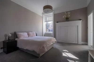 a bedroom with a bed with pink pillows and a window at Luxury Apartment/Flat Edinburgh City Centre in Edinburgh