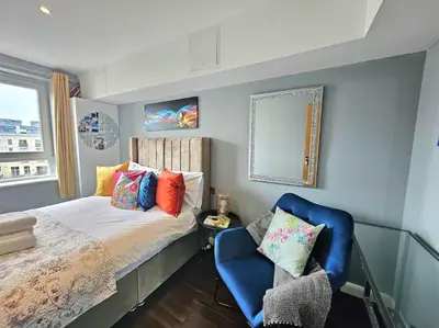 a bedroom with a bed and a blue chair at 4 Separate Beds, Sleeps 6, Beautiful 2 bed Apt in Edinburgh
