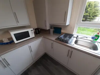 a kitchen with white cabinets and a sink and a microwave at Carvetii - Zelda House - 4 bedroom house, sleeps 8 in Oakley