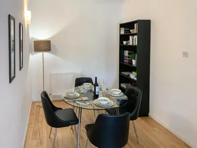 a dining room with a glass table and black chairs at Mill Court in Dunblane