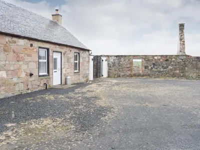 an old brick building with a parking lot in front of it at Dairy Cottage - Uk39522 in Maybole