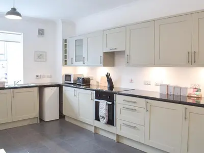 a kitchen with white cabinets and black counter tops at Dairy Cottage - Uk39522 in Maybole