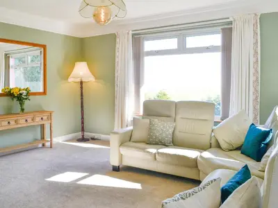 a living room with a couch and a window at Cairncroft Cottage in Colfin