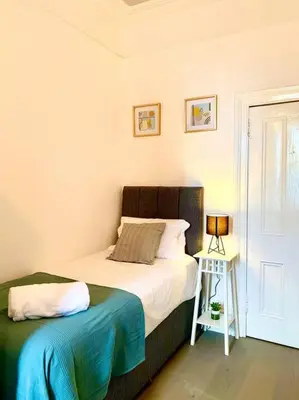 a bedroom with a bed and a table with a lamp at Historic 2-Bed Paisley Retreat, Airport & Station in Paisley