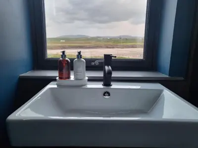 a sink with two bottles on it in front of a window at Machrie View in Port Ellen