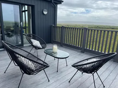 a patio with three chairs and a table on a deck at Machrie View in Port Ellen