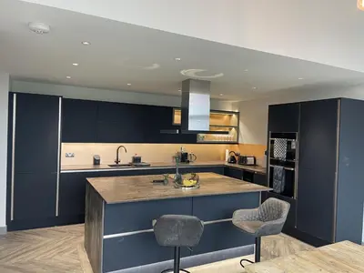 a kitchen with dark blue cabinets and a kitchen island at Machrie View in Port Ellen