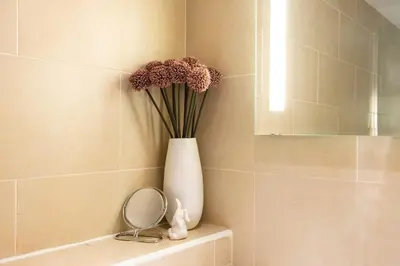 a white vase with flowers sitting on a shelf in a bathroom at Gorgeous apartment in the heart of New Town in Edinburgh