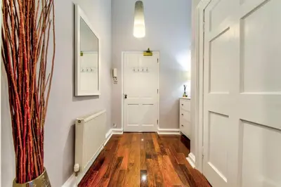 a hallway with white walls and wooden floors and a door at Gorgeous apartment in the heart of New Town in Edinburgh