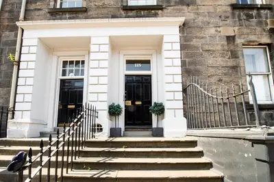 a building with a black door and stairs in front at Gorgeous apartment in the heart of New Town in Edinburgh