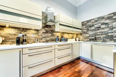 a kitchen with white cabinets and a wooden floor at Gorgeous apartment in the heart of New Town in Edinburgh
