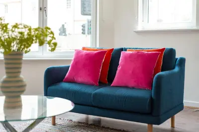a blue couch with pink pillows in a living room at Ground Floor 2 Bed Flat Slateford in Edinburgh