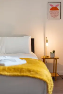 a bedroom with a bed with a yellow blanket on it at Ground Floor 2 Bed Flat Slateford in Edinburgh