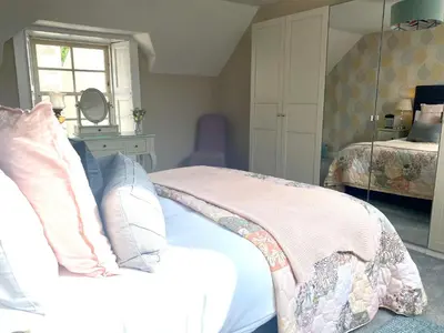 a bedroom with a bed and a mirror at Charming Cardoon Cottage in beautiful village in Comrie