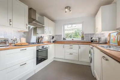 a white kitchen with white cabinets and a window at Charming Cardoon Cottage in beautiful village in Comrie