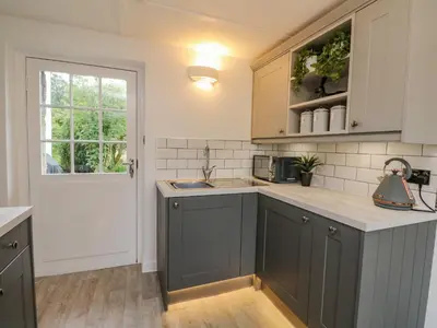 a kitchen with gray cabinets and a sink and a window at Inglis Nook Cottage in Lochearnhead