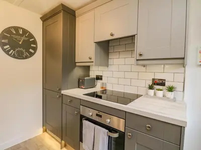 a kitchen with gray cabinets and a clock on the wall at Inglis Nook Cottage in Lochearnhead