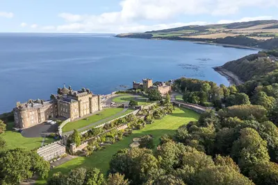 an aerial view of a castle on the shore of a lake at Clocktower - Culzean Castle in Maybole
