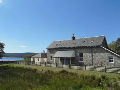 an old stone house on the shore of a lake at Achaglachgach Stables in Tarbert