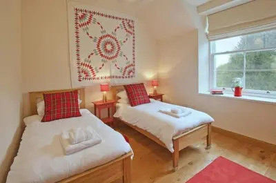 a bedroom with two beds and a window and a rug at Achaglachgach Stables in Tarbert